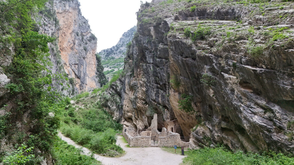 Vista dell'Abbazia di San Martino in Valle, che è stata costruita nella gola rocciosa dei monti della Majella, circondata da ripide scogliere e aree verdi.