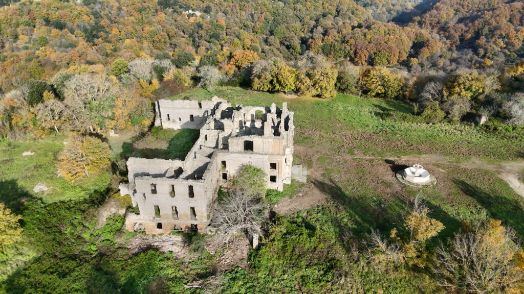 I resti della chiesa e del monastero di San Bonaventura nel Parco Naturale di Monterano, visti dall'alto. L'edificio rinascimentale giace tranquillo in mezzo al bosco autunnale.