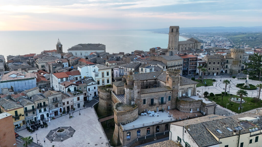 Veduta aerea del Castello Caldoresco di Vasto con gli edifici storici circostanti e il mare Adriatico sullo sfondo.