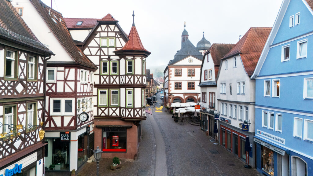 Early morning view of a cobbled street in Lohr am Main lined with timber-framed houses, leading toward the historic town hall.