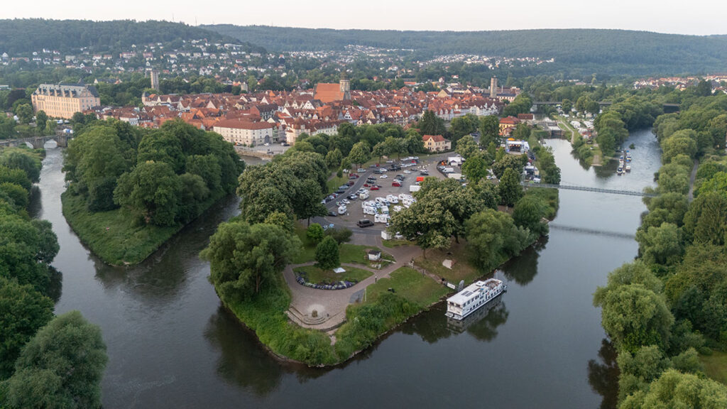 Vista aerea del centro storico di Hann. Münden nella Bassa Sassonia, Germania, con campeggio sulla riva del fiume, camper e tetti rossi sullo sfondo