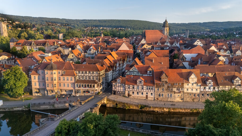 Vista aerea del centro storico di Hann. Münden nella Bassa Sassonia, Germania, con case a graticcio, tetti rossi, ponte in pietra e la chiesa di San Biagio al tramonto.