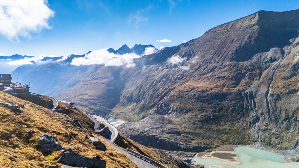 Winding road along the Grossglockner High Alpine Route overlooking the deep mountain valley and turquoise glacier lake in Carinthia, Austria.