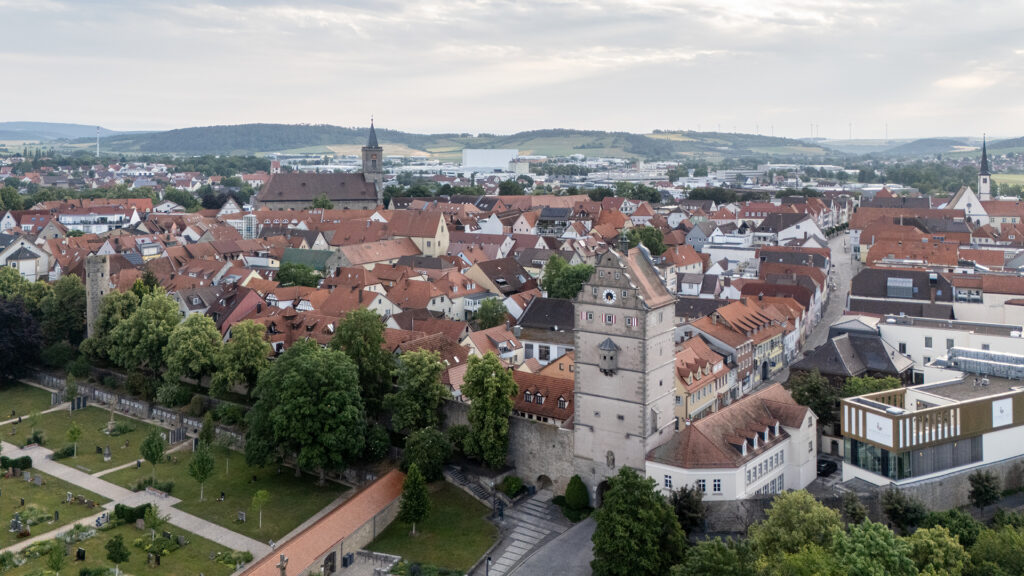 Aerial view of Bad Neustadt an der Saale with the historic Hohntor gate tower, red rooftops, city walls and the Saale valley in Lower Franconia, Germany.